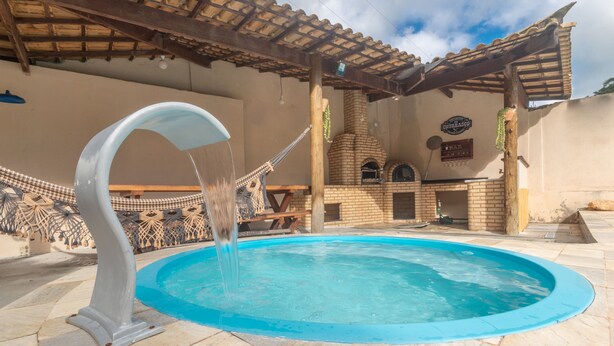 A swimming pool with a water feature, a brick oven, and a sign that reads "Bar". - Clim House in Buzios  (Altos de Búzios Armação dos Búzios)