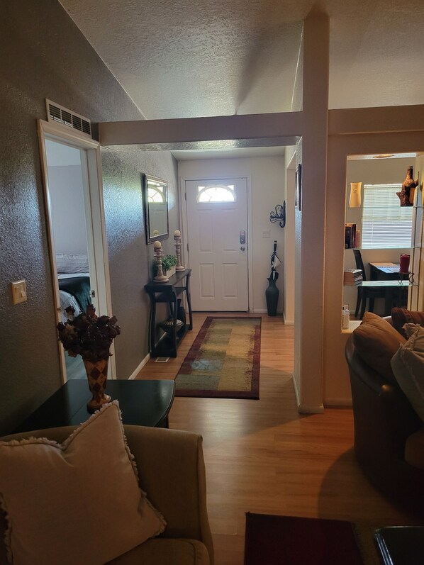 A living room with a sofa, a coffee table, and a rug. There is a door leading to another room.