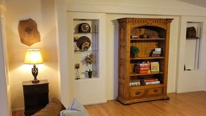 A living room with a leather sofa, a wooden bookcase, a lamp, and a wall-mounted decorative piece. - Saguaro National Park Westside retreat.   (Tucson)