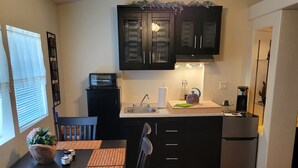A compact kitchen with dark cabinets, a wooden dining table, and a ceiling fan. - Saguaro National Park Westside retreat.   (Tucson)