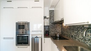 A modern kitchen with stainless steel appliances, a large sink, and a tiled backsplash. - WELCS APARTAMENTO 059 EMP con vista al canal (Empuriabrava)