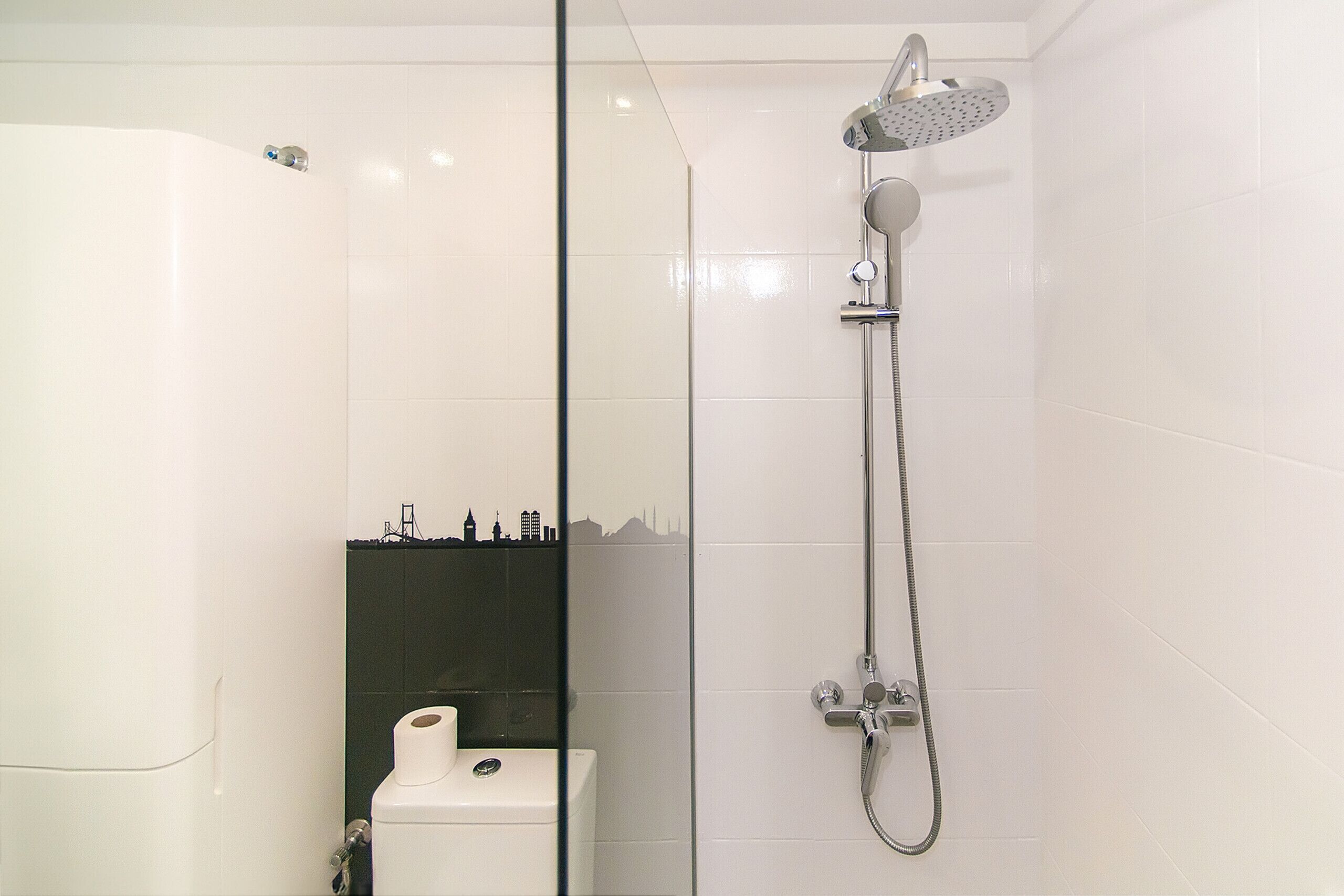 A modern bathroom with a glass shower enclosure, a toilet, and a sink.