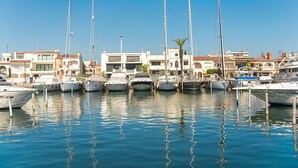 A marina with multiple boats docked, surrounded by buildings with distinct architectural styles. - WELCS APARTAMENTO 059 EMP con vista al canal (Empuriabrava)