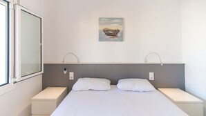 A bedroom with a bed, two bedside tables, a nightstand, a window, and a painting on the wall. - WELCS APARTAMENTO 059 EMP con vista al canal (Empuriabrava)