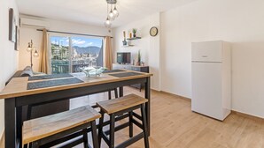 A modern kitchen with a wooden table and bench, a refrigerator, and a view of a marina through large windows.