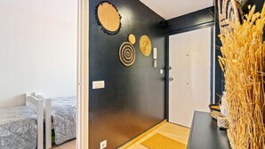 Quarto com parede preta, porta branca e pequena mesa com cesta de palha.