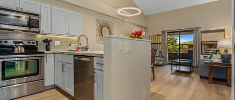 A modern kitchen with stainless steel appliances, white cabinetry, and a central island with a vase of flowers.