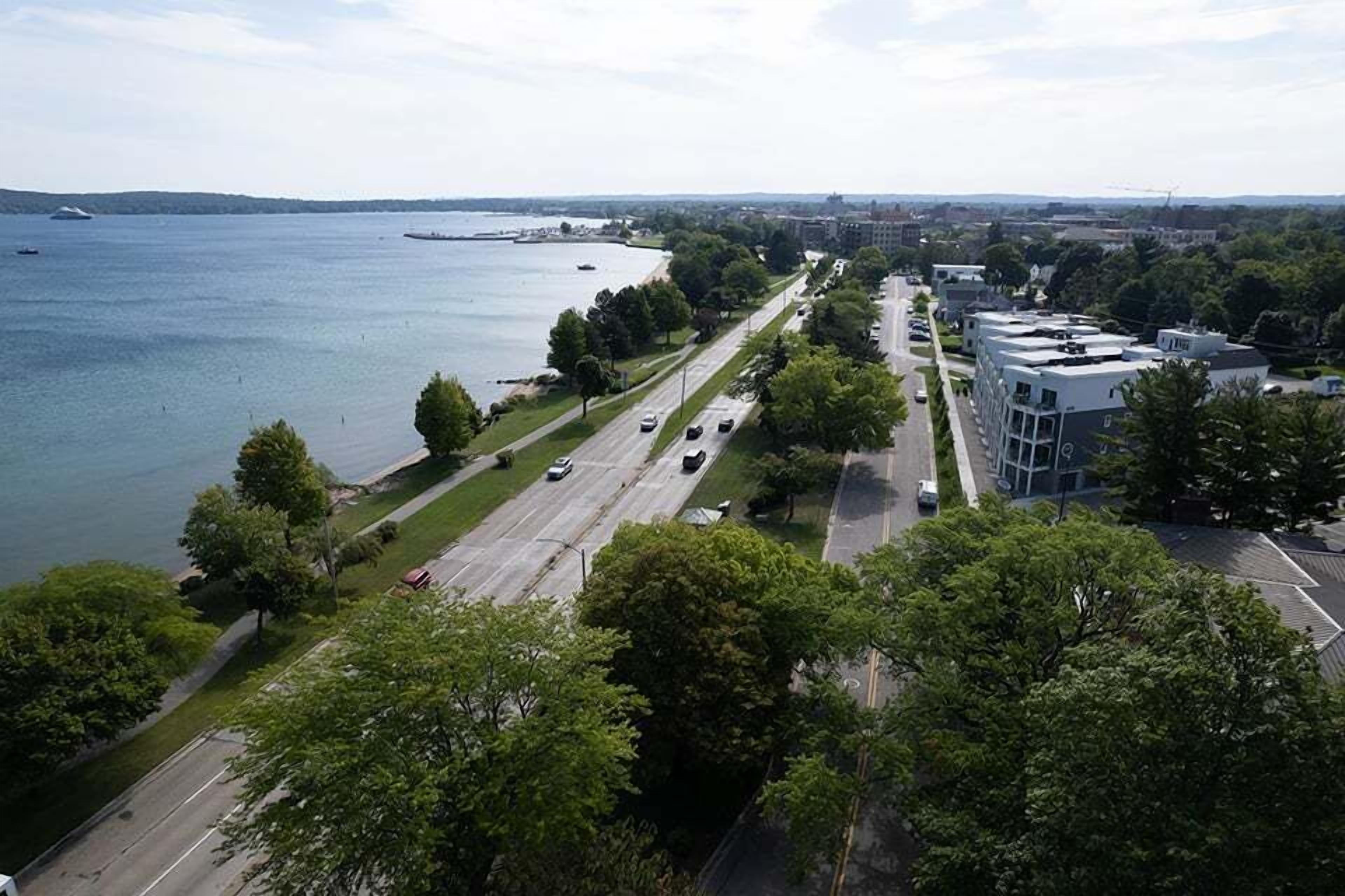 Ilmakuva rannikkotieltä, jossa näkyy rakennuksia, puita ja vesialuetta.