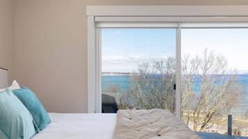 Une chambre avec un lit, une grande fenêtre et une vue sur la mer.