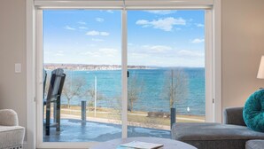 Una habitación con un amplio ventanal corredero que da a una vista de agua y una costa distante.
