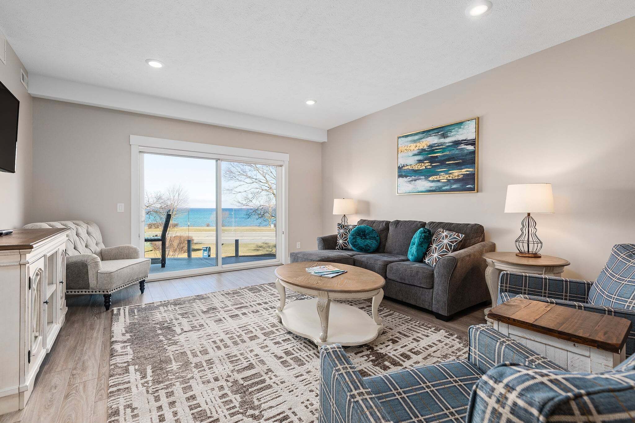 A living room with a sofa, a coffee table, a TV, and a view through a large window.