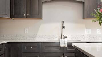 Una cocina con armarios oscuros, encimera blanca y suelo de madera.