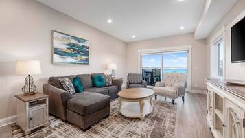 A living room with a sofa, ottoman, coffee table, and a TV on a cabinet.