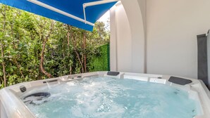 Uma banheira de hidromassagem com vista para um cercado verde exuberante e uma parede branca.