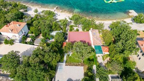 Vista aérea de uma área residencial costeira com casas, águas turquesa cristalinas e uma estrutura verde flutuante.