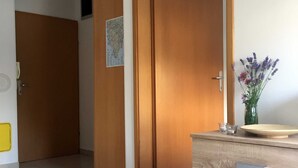 Une pièce avec une armoire en bois, un sol carrelé et une porte donnant sur une autre pièce.