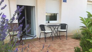 Une terrasse extérieure avec une table et des chaises, entourée d’un jardin agrémenté de plantes de lavande et d’un petit jardin de rocaille.