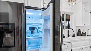 Ein Edelstahl-Kühlschrank mit Wasserspender, integriertem Eisbereiter und einem separaten Gefrierfach.