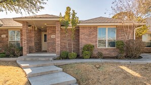 A two-story brick house with a front porch, numbered 1603 and 1605, and a well-maintained lawn. - Right At Home-Midland Monterrey House (Midland)