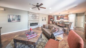 A spacious living room with a fireplace, a dining area, and a kitchen in the background. - Right At Home-Midland Monterrey House (Midland)