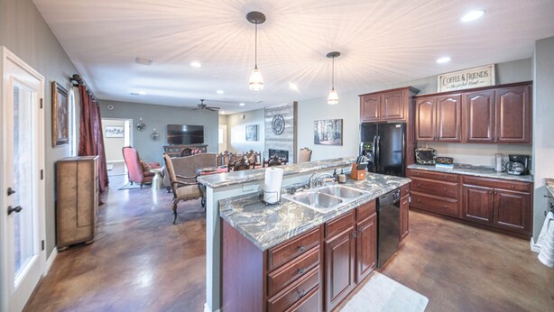 A spacious kitchen with granite countertops, wooden cabinets, and a central island. - Right At Home-Midland Monterrey House (Midland)