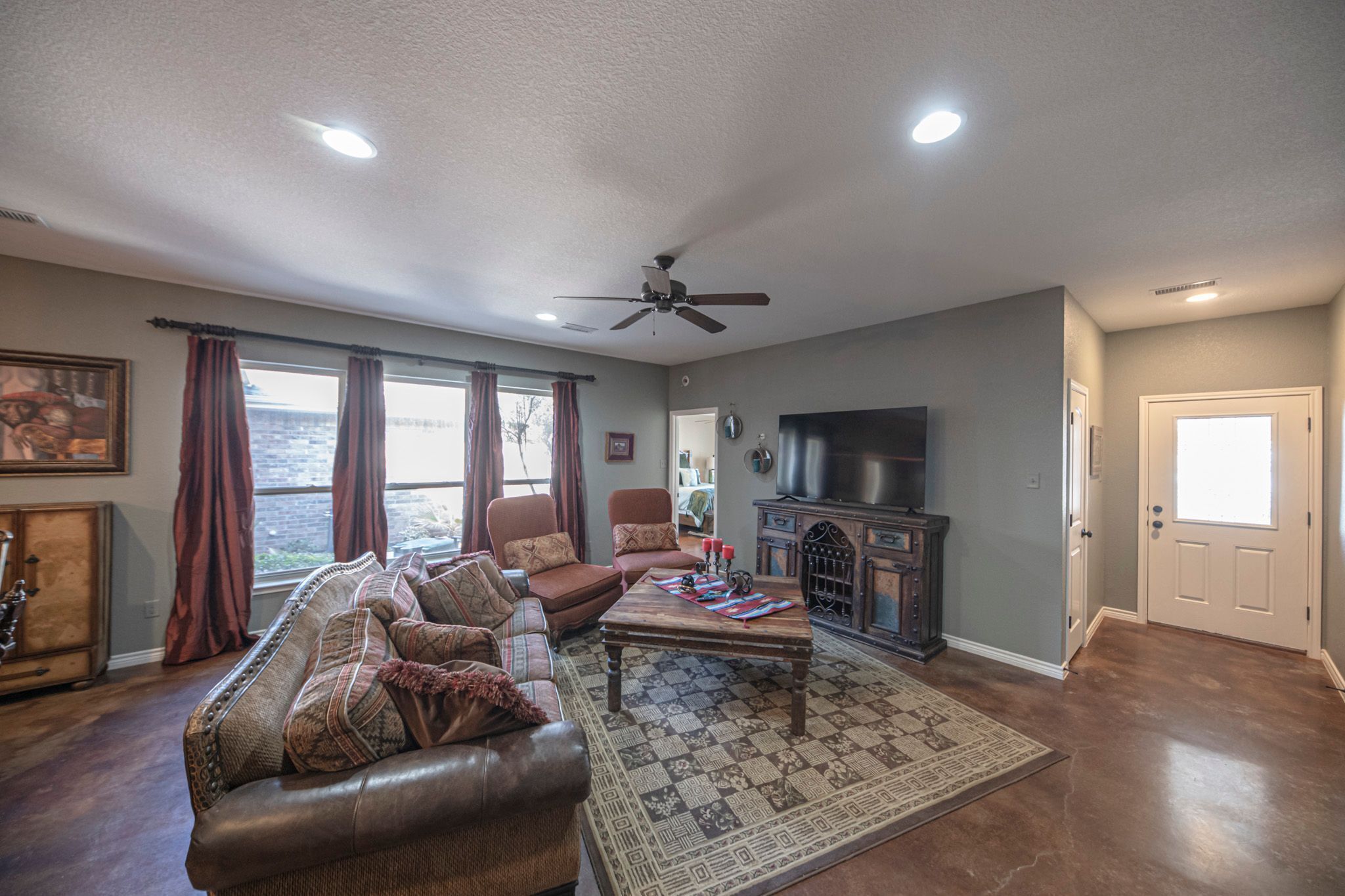 A living room with a leather sofa, a coffee table, a fireplace, and a television.