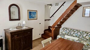 Una stanza con una scala in legno, un divano, un tavolo in legno, un armadio e uno specchio.