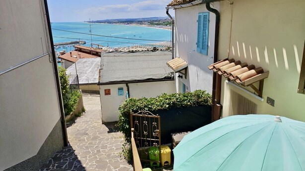 Un vialetto stretto che conduce a una proprietà sul lungomare, con vista sul mare e sulle barche.