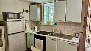Una cucina compatta con forno a microonde, lavello e pensili.