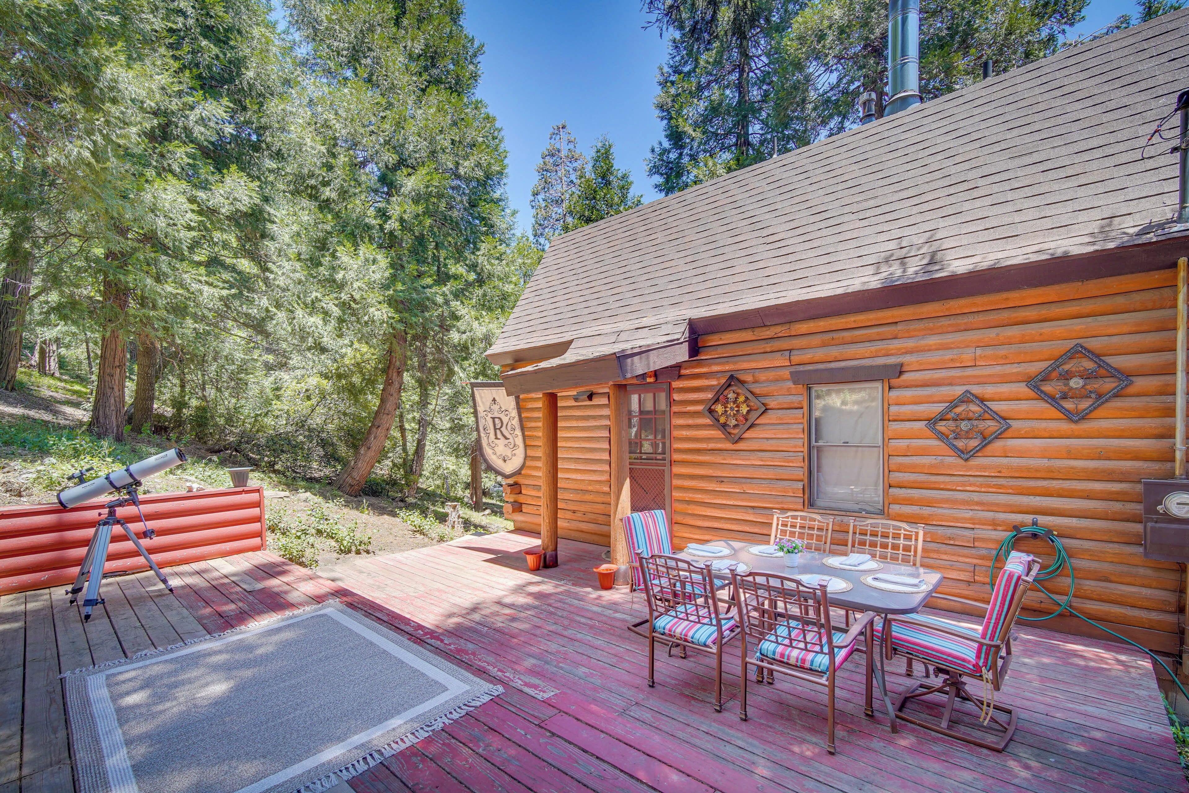 Eine Blockhütte mit einer Terrasse, einem Teleskop und einem Essbereich mit Stühlen und einem Tisch.