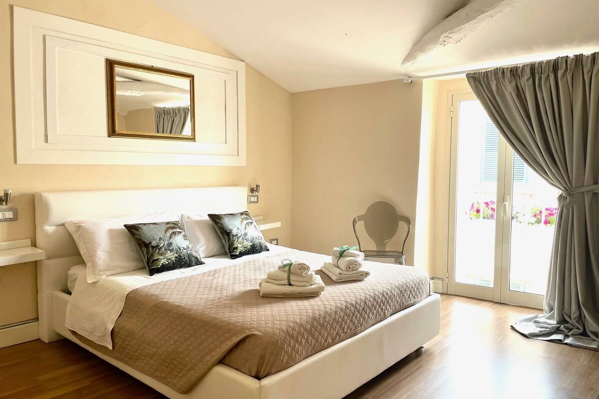 Een hotelkamer met een groot bed, een nachtkastje, een stoel en een raam met gordijnen.