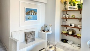 A modern living room with a white sofa, a framed painting, and a wooden shelf with various decorative items. - Residenza Donna Peppina Tropea (Tropea)