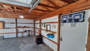 Un garage avec des poutres en bois, un panier de basket et une porte sur laquelle est fixé un filet de basket.