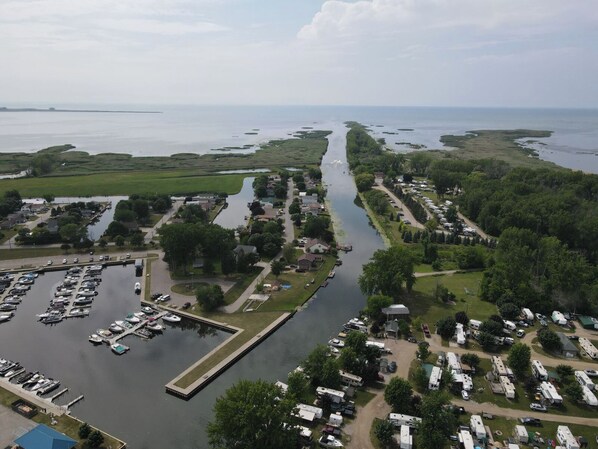 Vue aérienne d’un terrain de camping au bord d’un lac, avec des quais pour bateaux, un espace de stationnement pour les véhicules de loisirs et une rivière qui le traverse.