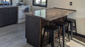Une cuisine moderne avec des meubles de couleur sombre, un îlot central doté de tabourets, une cuisinière et une fenêtre offrant une belle vue.
