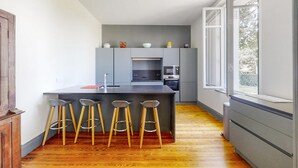 Une cuisine moderne dotée d’un îlot central, de tabourets de bar et d’appareils électroménagers intégrés.
