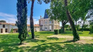 Une grande maison à deux étages, dotée d’une tour imposante et d’une pelouse bien entretenue.