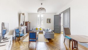 Un salon spacieux avec une cheminée, un canapé, une table à manger et une grande fenêtre.