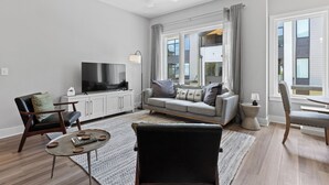 Una sala de estar moderna con un sofá, sillones, una mesa de centro y un televisor.
