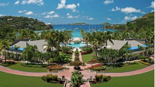 Ein Resort mit einem zentralen Pool, Palmen und Blick auf das Meer.
