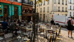 Outdoor cafe seating with tables and chairs, a tree, and buildings in the background. - Montmartre & Eiffel Tower View – In the Heart of Authentic Paris (Paris)
