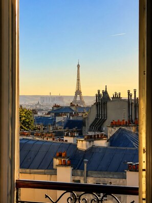 A view of the Eiffel Tower from a window overlooking a cityscape with rooftops and buildings. - Montmartre & Eiffel Tower View – In the Heart of Authentic Paris (Paris)