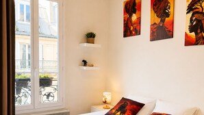 A bedroom with a bed, bedside tables, a lamp, a window with curtains, and wall art. - Montmartre & Eiffel Tower View – In the Heart of Authentic Paris (Paris)