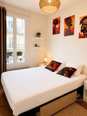 Un dormitorio con cama, mesitas de noche, lámpara, ventana con cortinas y decoración en la pared.