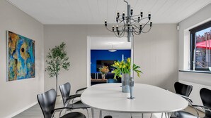 Una sala conferenze moderna con un tavolo rotondo, sedie nere, un lampadario, un quadro, una pianta e una finestra con vista.