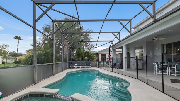 Una piscina exterior con zona cubierta, mobiliario de jardín y un patio con mesas y sillas.