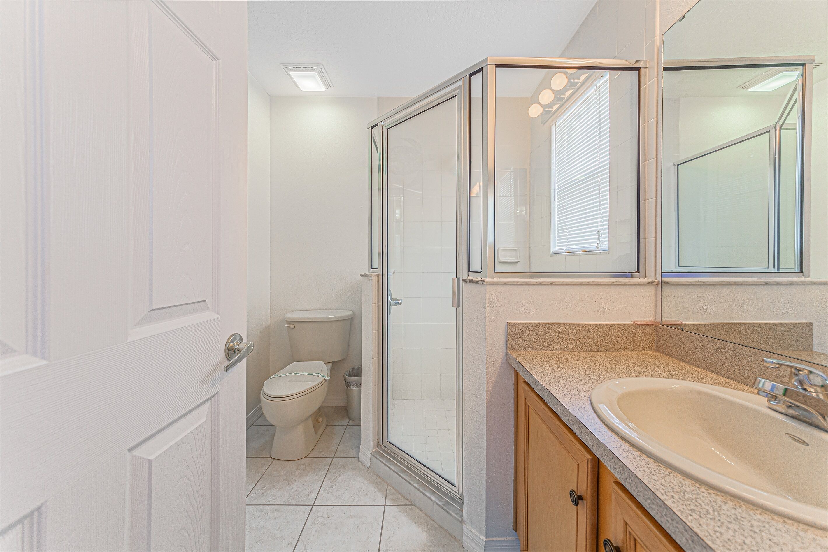 A bathroom with a glass shower enclosure, a toilet, and a sink with a countertop.