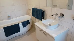 Une salle de bain moderne avec une baignoire blanche, un lavabo blanc et un miroir au-dessus du lavabo.