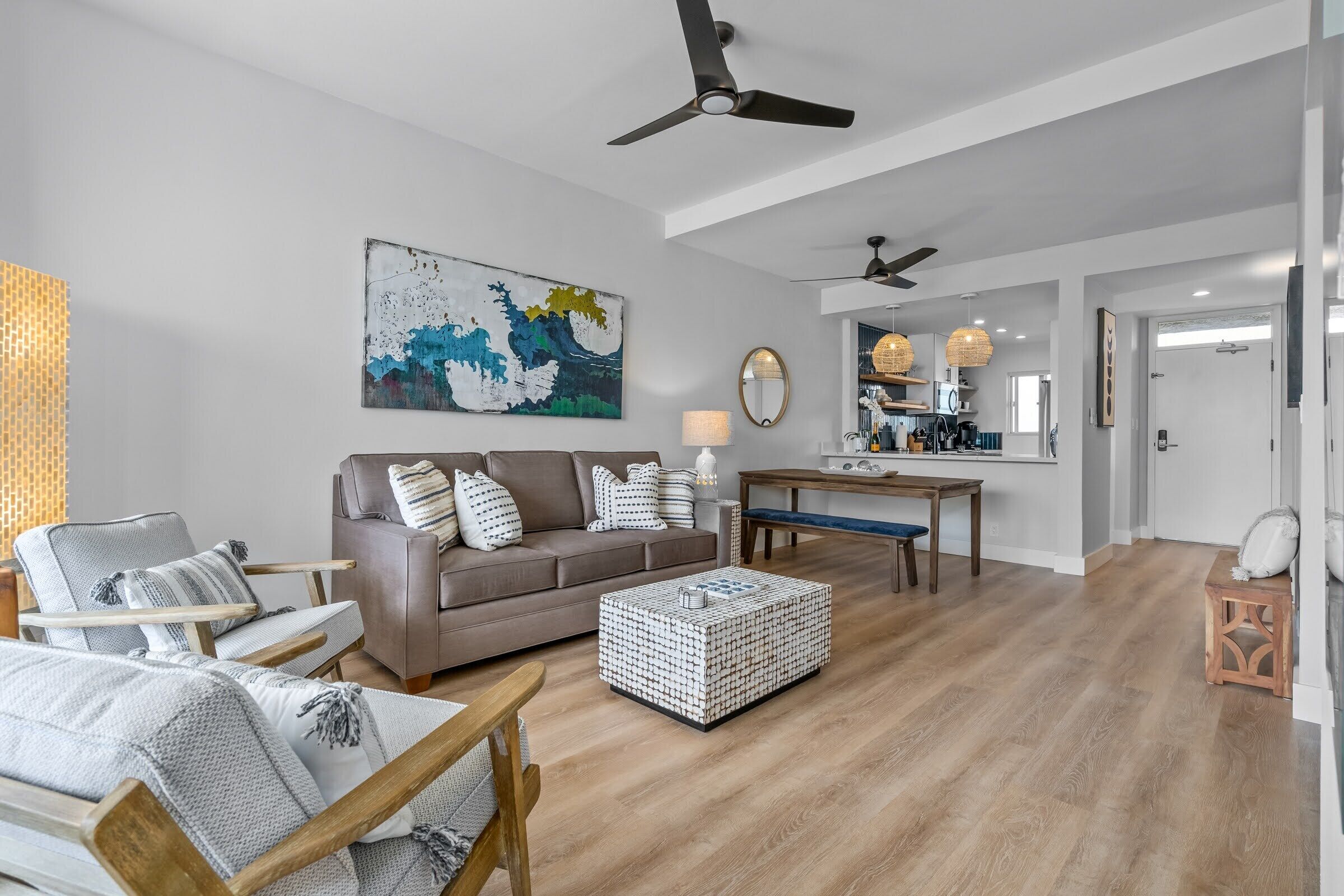 A spacious living room with a brown sofa, a wooden coffee table, and a dining area with a table and chairs.