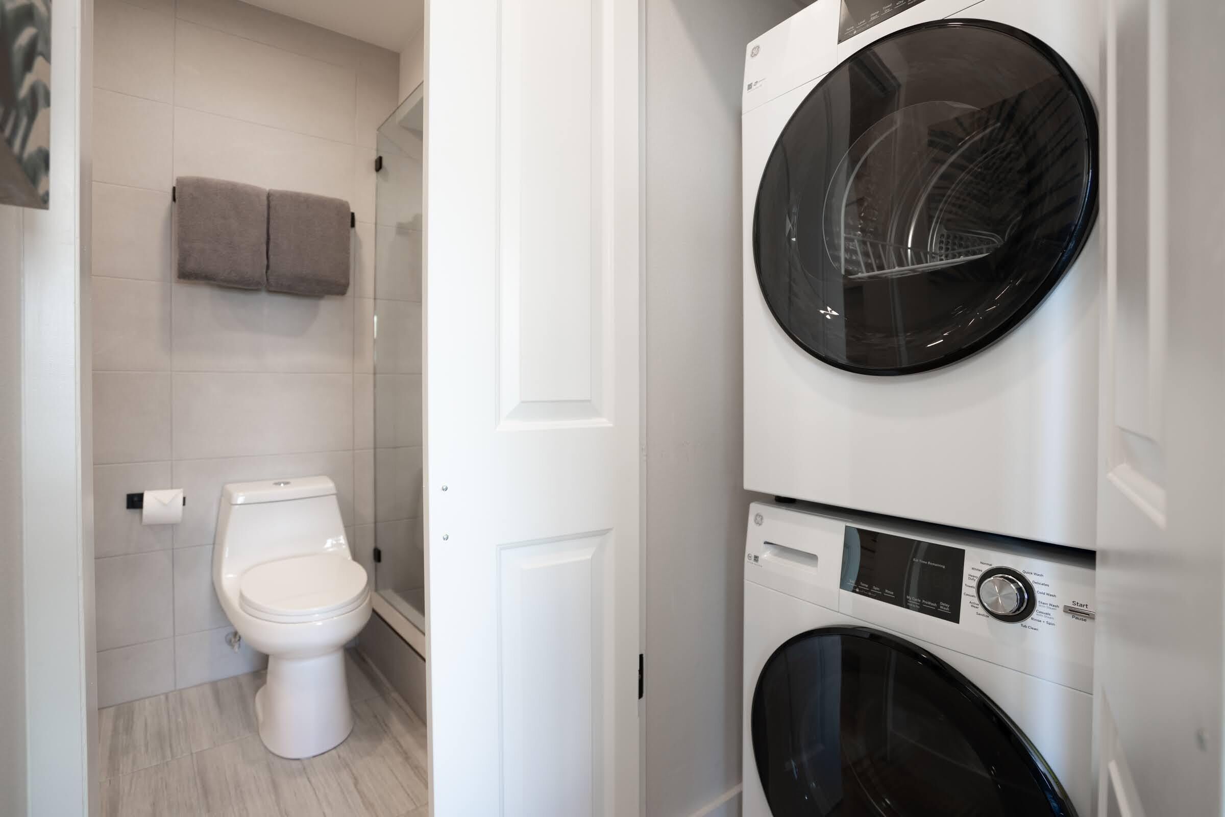 Une petite salle de bain comprenant des toilettes, un lave-linge et un porte-serviettes.